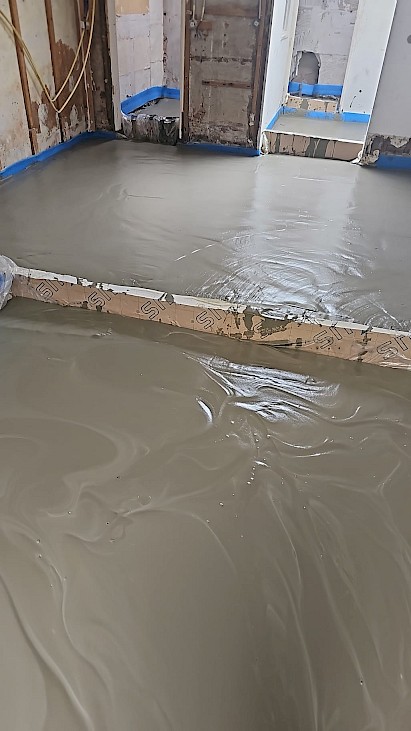 Het storten en verwerken van schuimbeton om een vloer te isoleren tijdens een renovatie project.